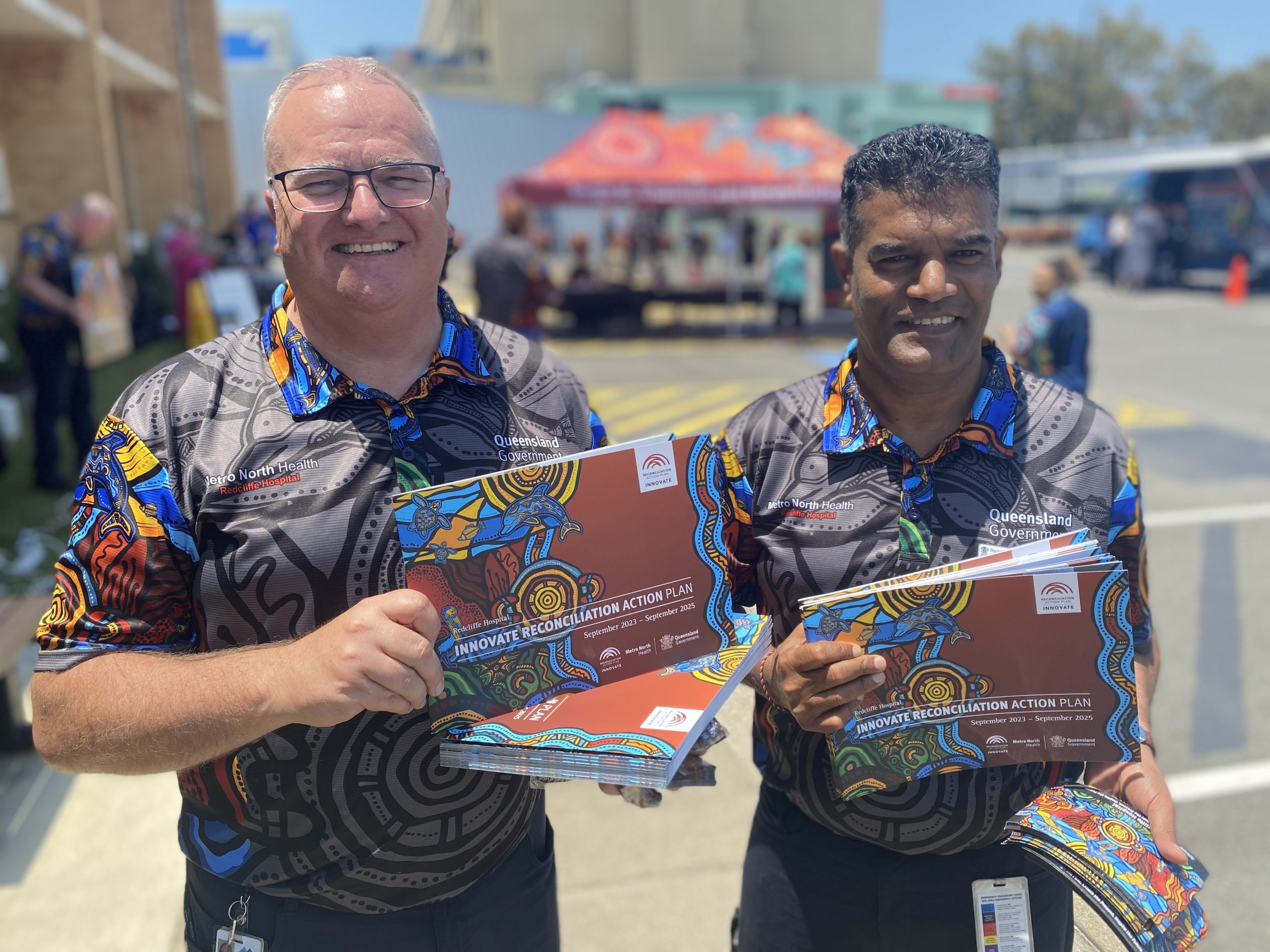 Two men holding copies of the Redcliffe Hospital Reconciliation Action Plan