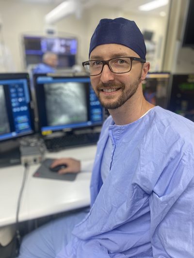 Clinician in scrubs smiling at the camera