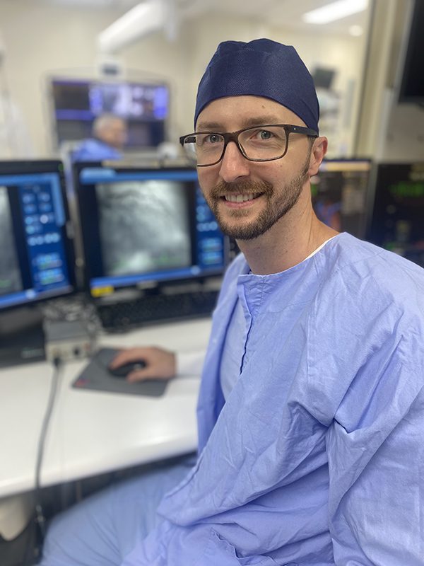 Clinician in scrubs smiling at the camera