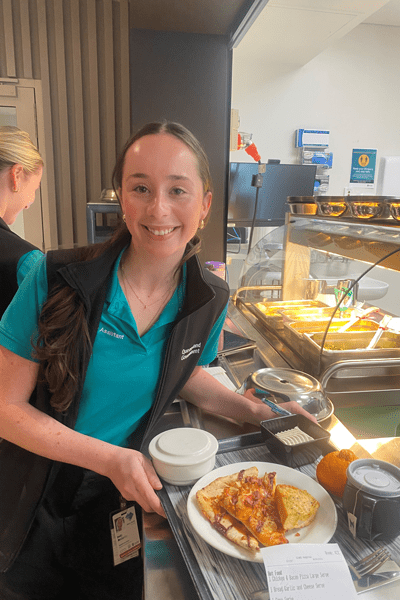 Staff serving the pizza night meal in the dining room