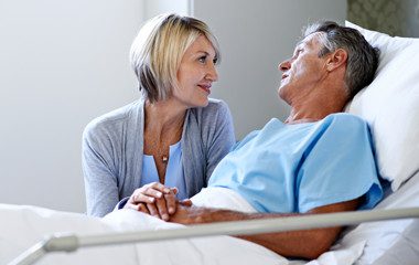 Patient in bed holding hands with a visitor