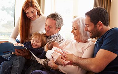 Image of an extended family looking a a book.