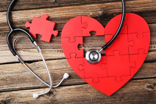 Red,Puzzle,Heart,With,Stethoscope,On,Brown,Wooden,Background